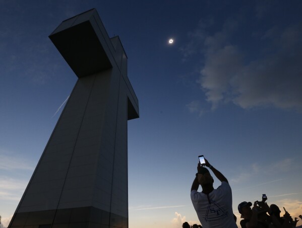 FILE - A total solar eclipse is seen above the Bald Knob Cross of Peace Monday, Aug. 21, 2017, in Alto Pass, Ill. Small towns and rural enclaves along the path of April’s 2024 total solar eclipse are steeling for huge crowds of sun chasers who plan to catch a glimpse of day turning into dusk in North America. (AP Photo/Charles Rex Arbogast, File)